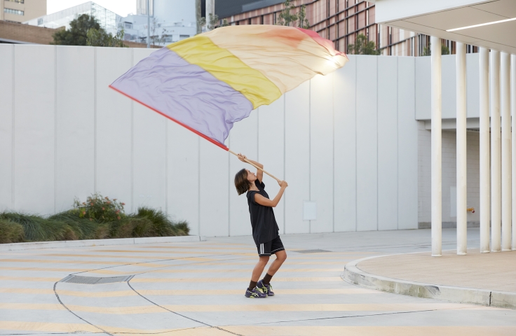 Image of artist Lauren Brincat waving a colourful flag 